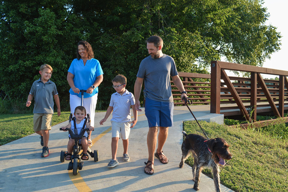 2024 Paragould Guide Cover featuring a family walking along a trail with a dog